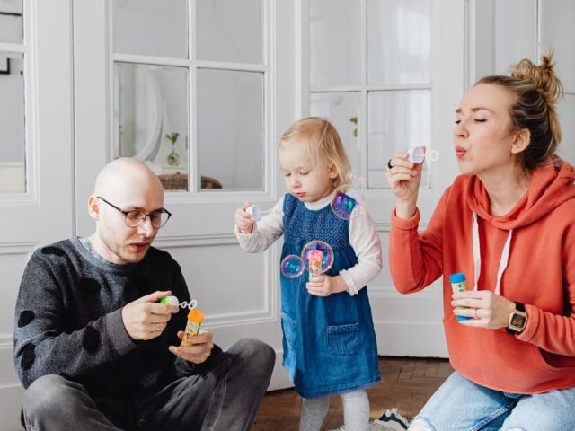 Family enjoying quality time blowing bubbles indoors, capturing joyful moments.